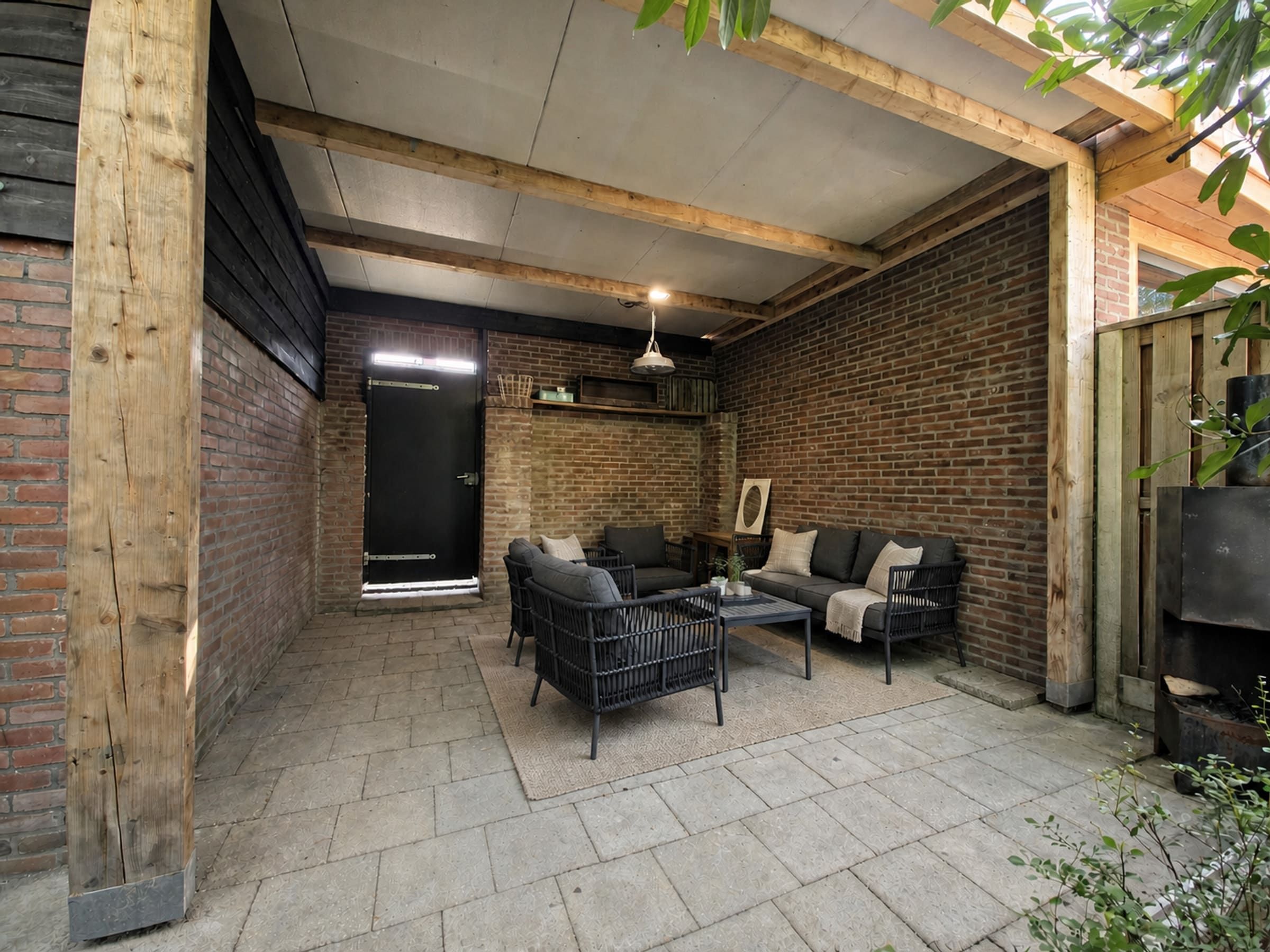 Verzorgde overdekte loungeplek achter in de tuin