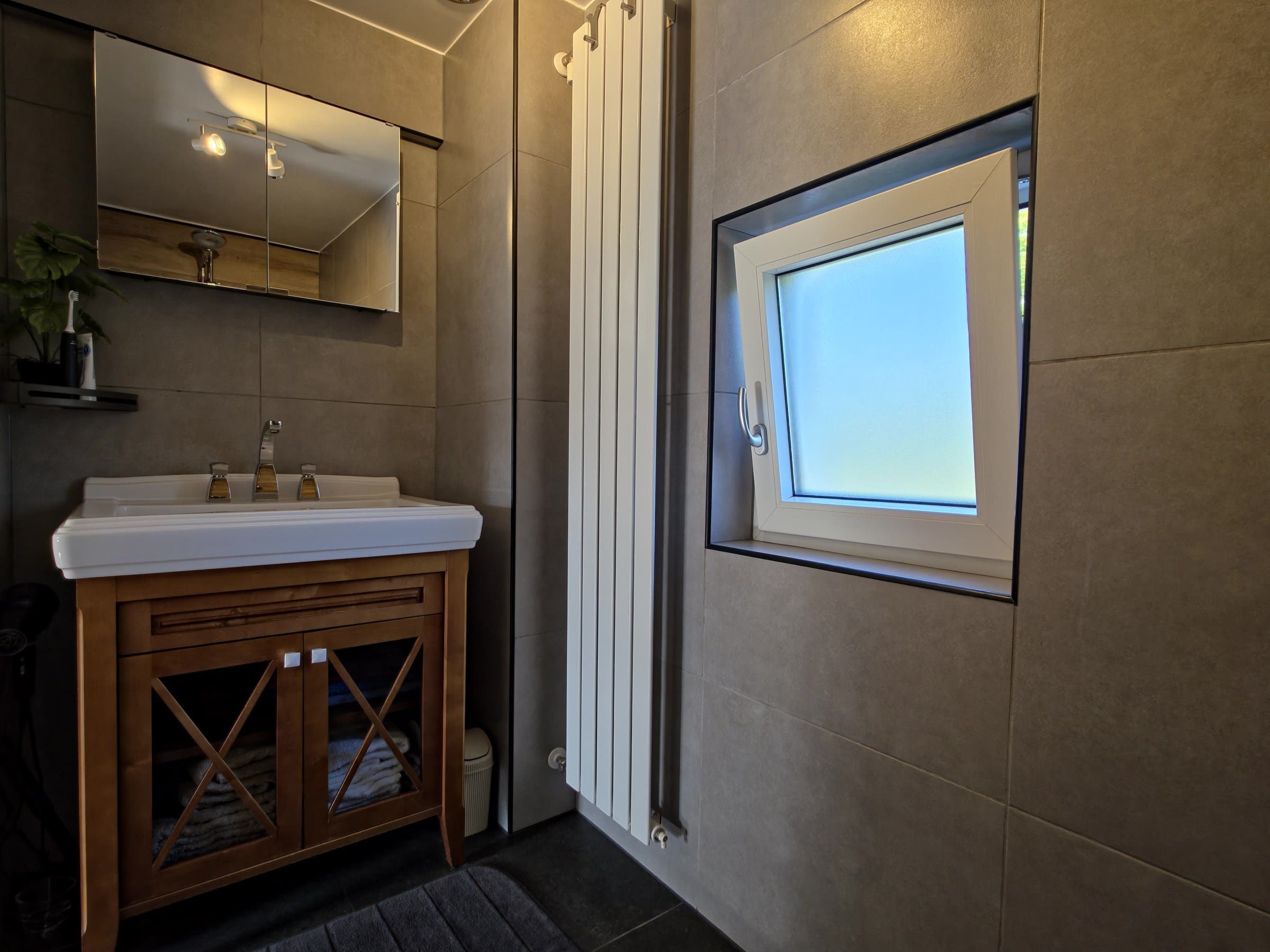 Wastafelmeubel, spiegel, radiator en raam in de badkamer