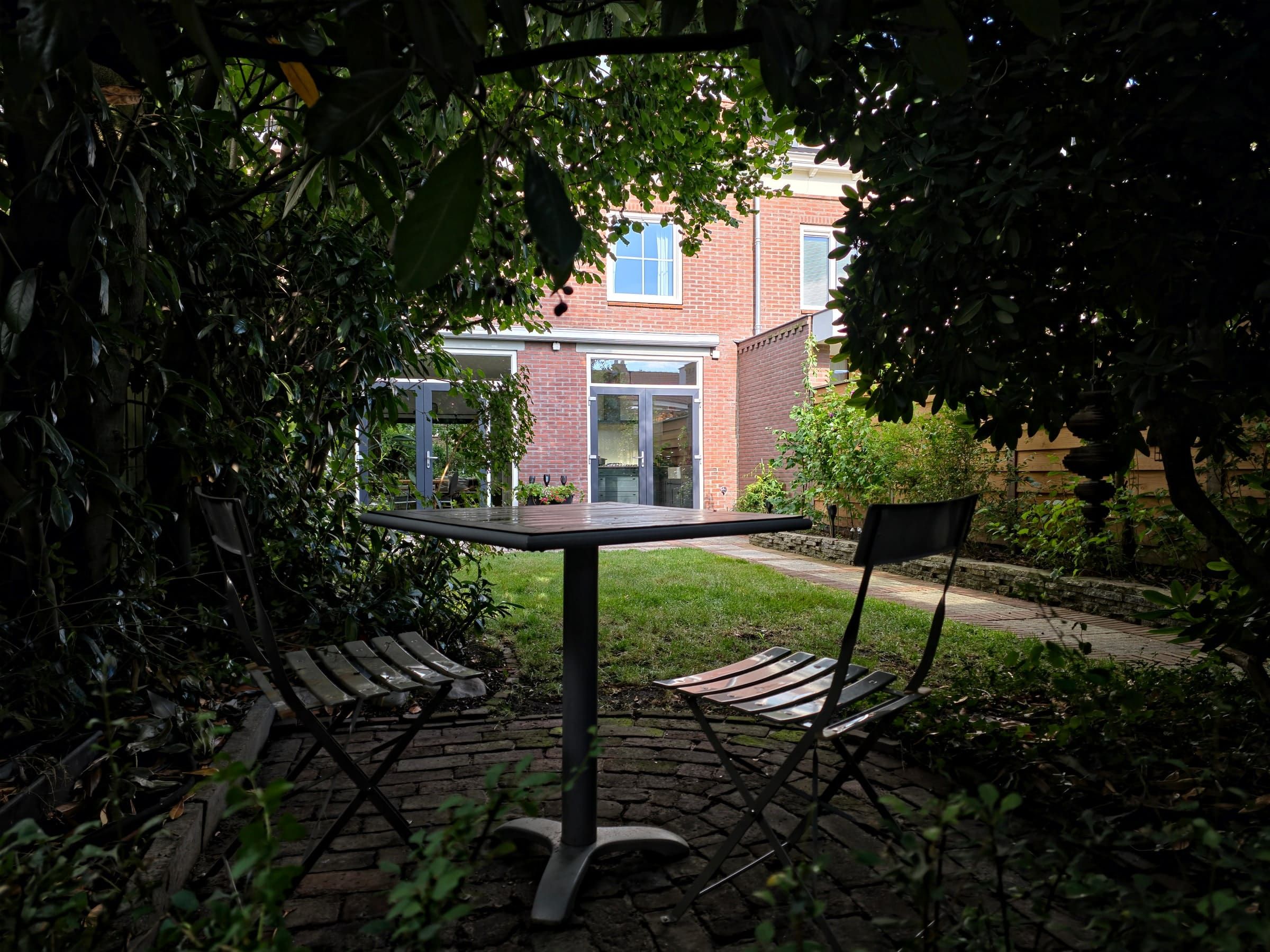 Sfeervolle zitplek onder het volwassen groen achter in de tuin