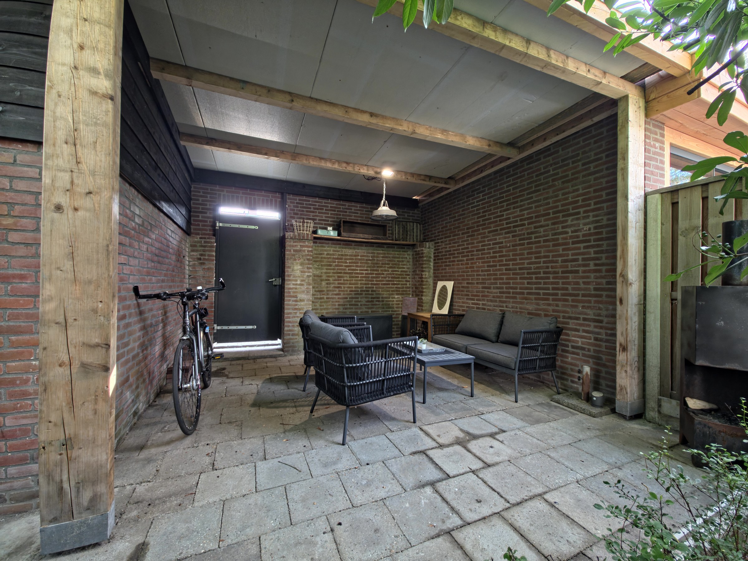 Verzorgde overdekte loungeplek achter in de tuin
