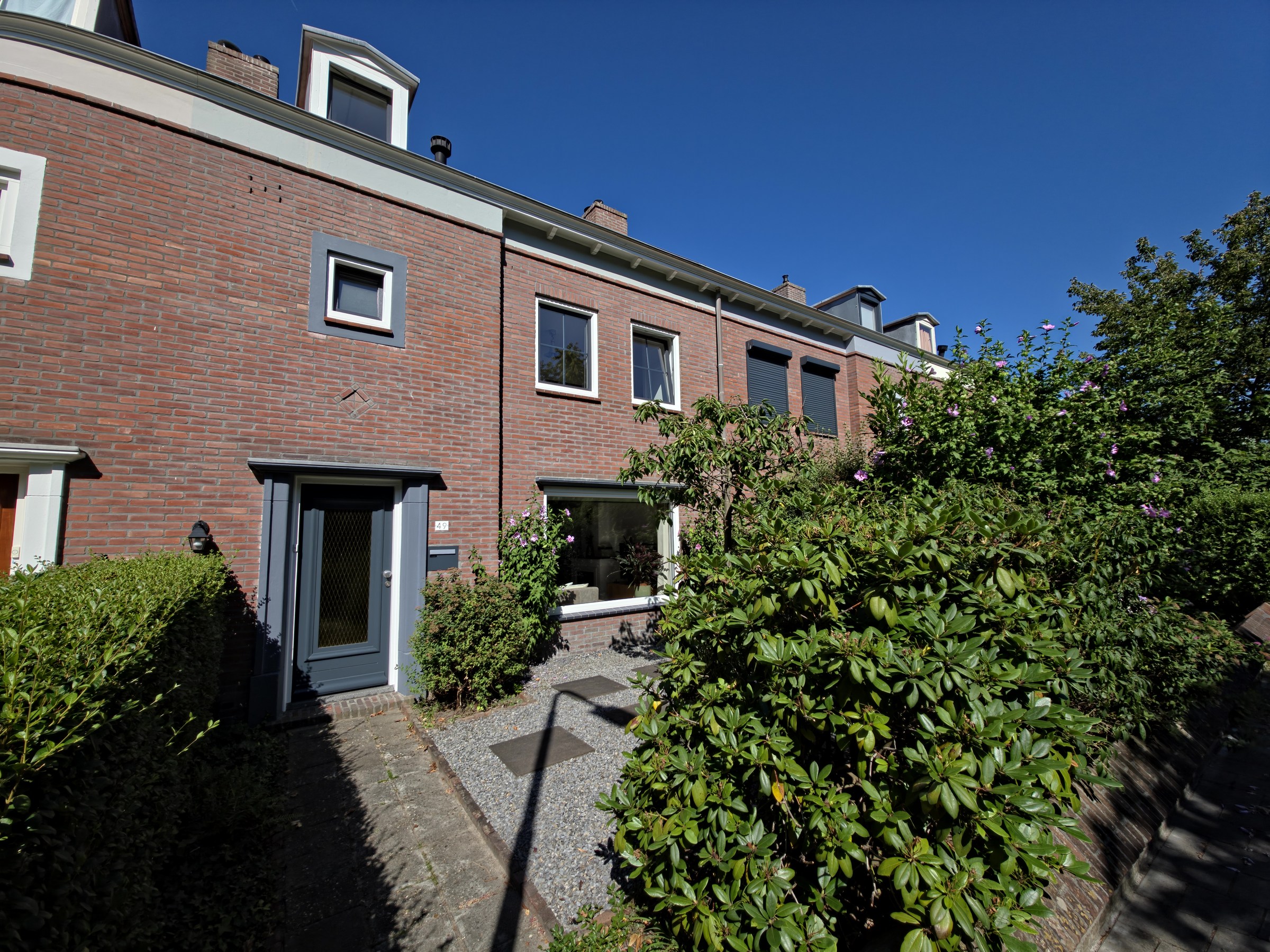 Schuin zicht op de voorgevel en de groene voortuin van Arendlaan 49