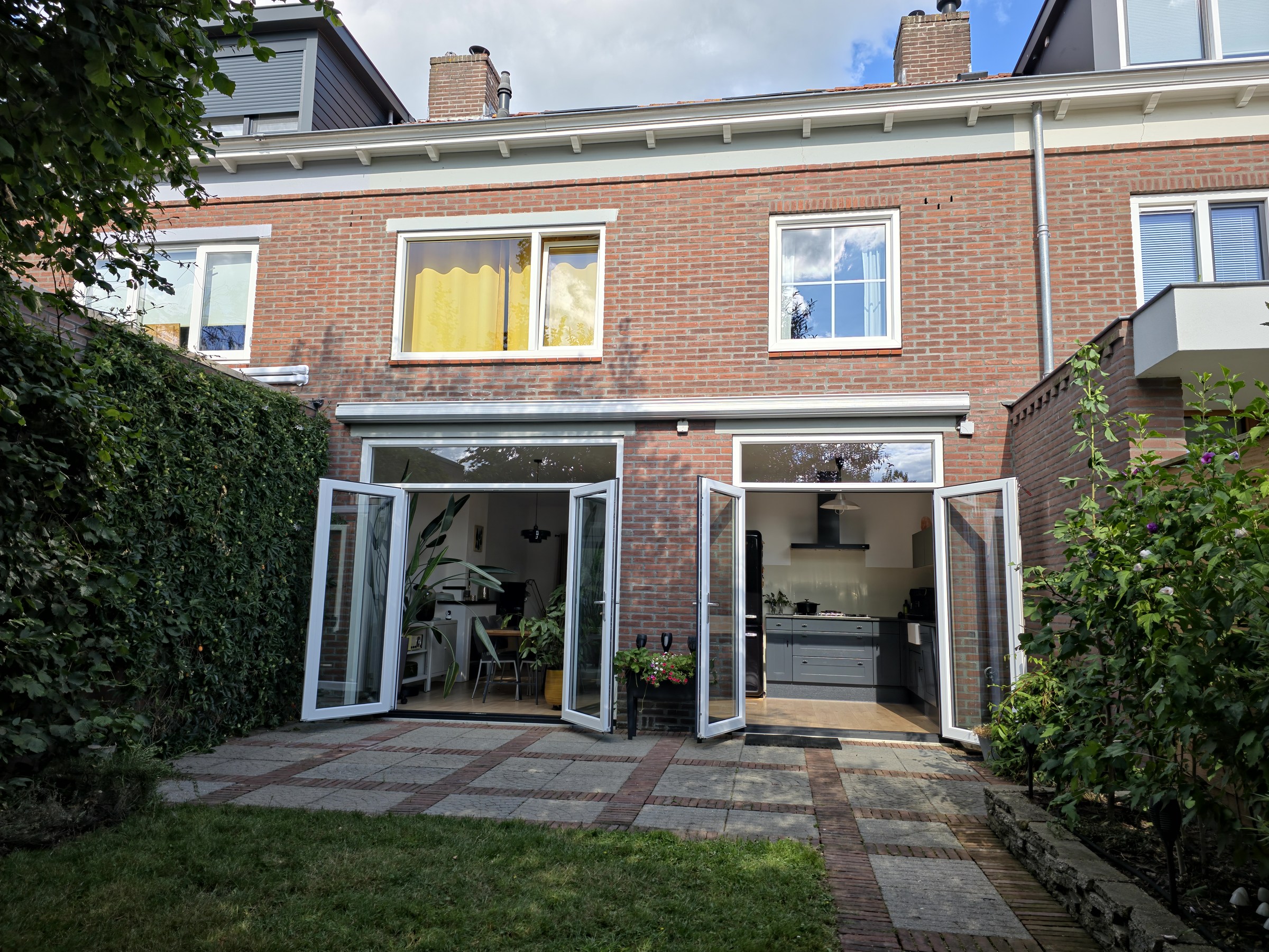 Evenwichtig frontaal beeld van de achtergevel en het terras